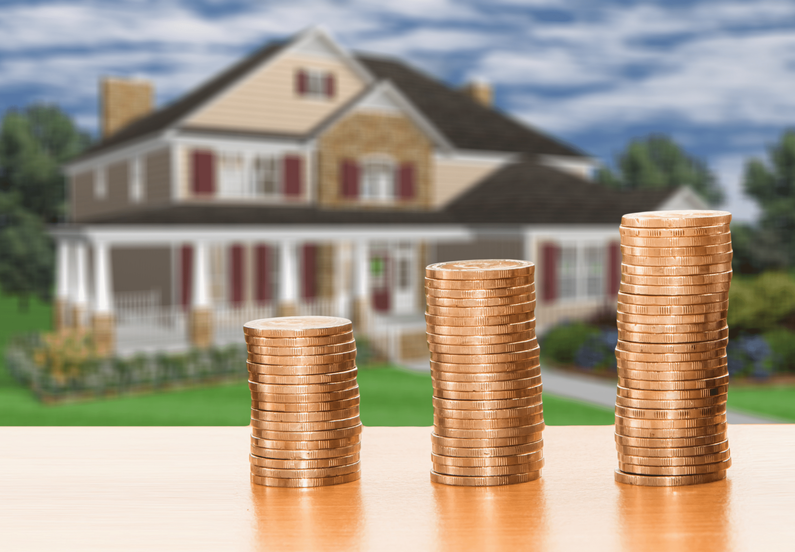 Header Immobilienertragssteuer im Überblick - Münzen aufgetürmt, dahinter ein Haus